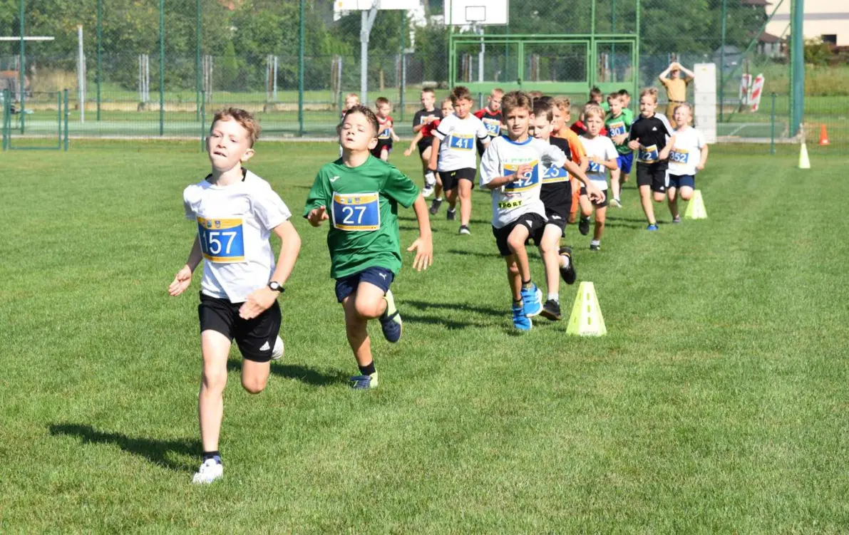 Grupa biegnących po boisku dzieci